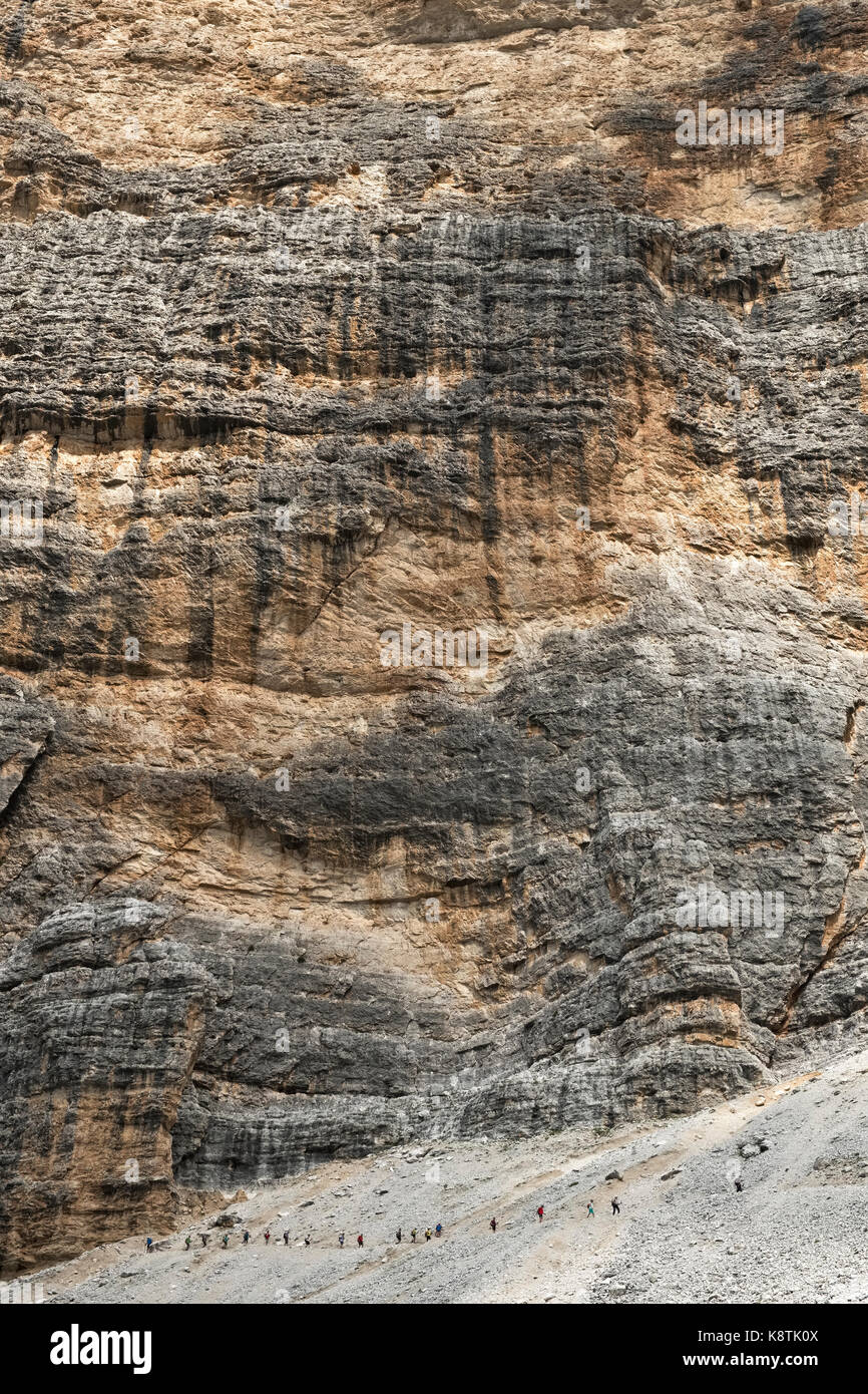 Die Dolomiten, Norditalien. Die winzigen Figuren der Wanderer unter der massiven Wand des Zimes de Fanes, auf der Alta Via 1 Long distance Path Stockfoto