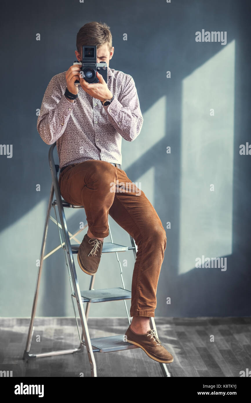 Portrait von stattlicher Mann mit retro Mitte Kamera im Studio. Fotograf Stockfoto