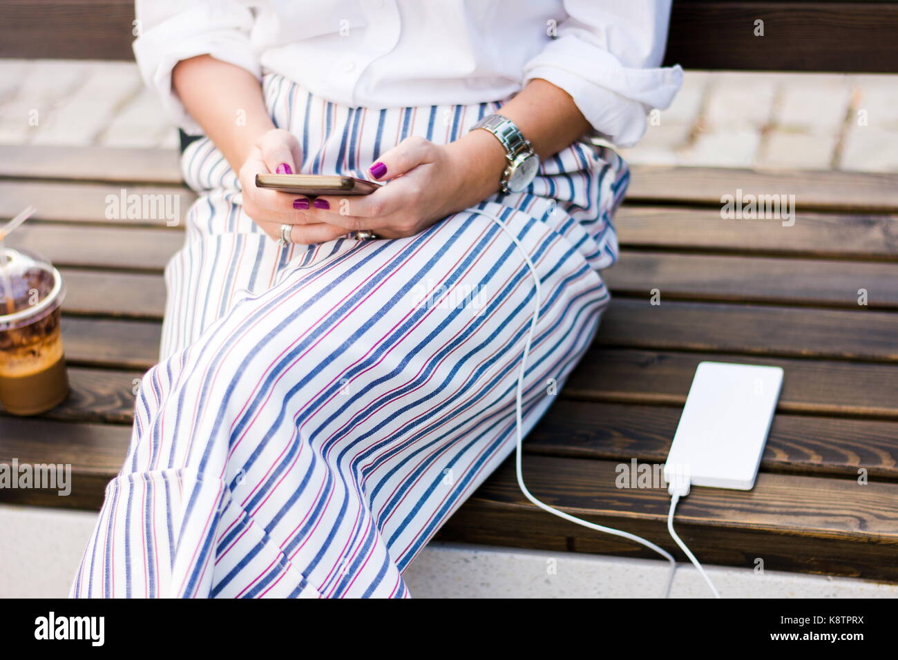 Mädchen mit Smart Phone während des Ladevorgangs auf dem Power Bank Stockfoto