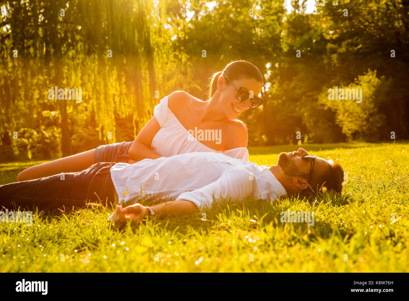 Eine schöne, junge Paare mit in das Gras in einem Park im Sonnenuntergang Stockfoto