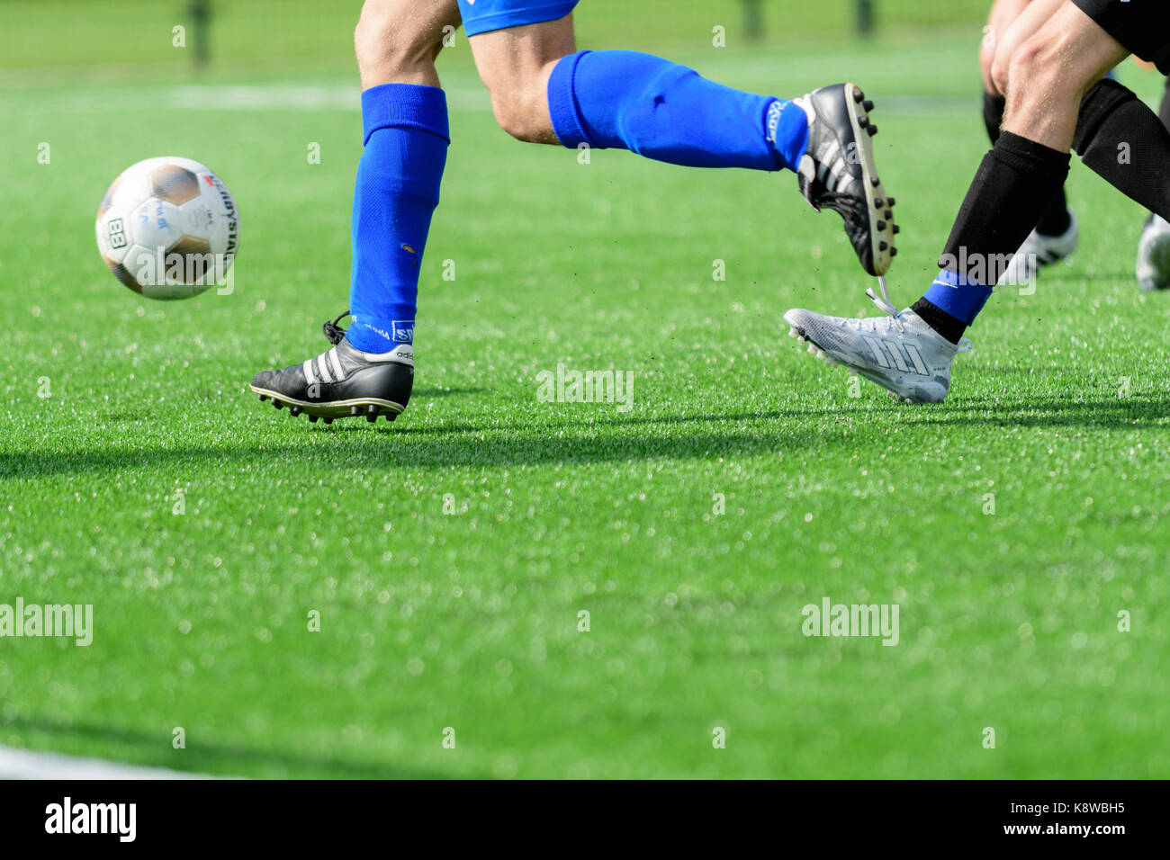 Beine von Fußball-Spieler und Ball bei einem Match auf Kunstrasen Stockfoto