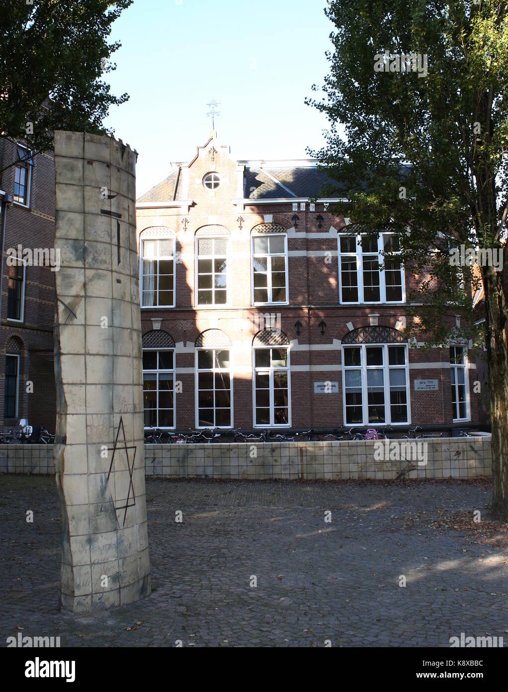 Ehemalige jüdische Schule (1886) im alten jüdischen Viertel von Leeuwarden, Friesland, Niederlande. Denkmal im Vordergrund. Stockfoto