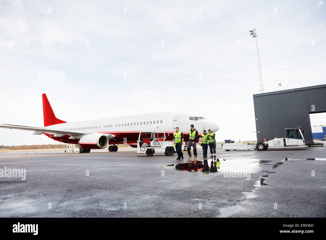 Arbeitnehmer zu Fuß mit dem Flugzeug Auf nasser Piste Stockfoto