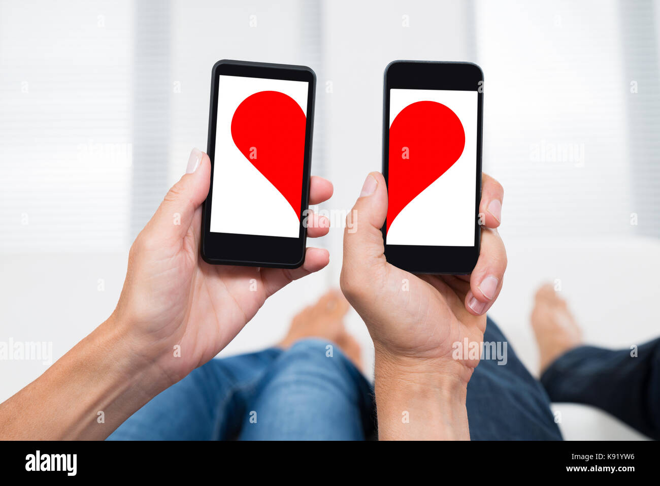 In der Nähe von zwei Menschen die Hände mit Mobiltelefonen, die zwei Hälften des Herzens Form Stockfoto