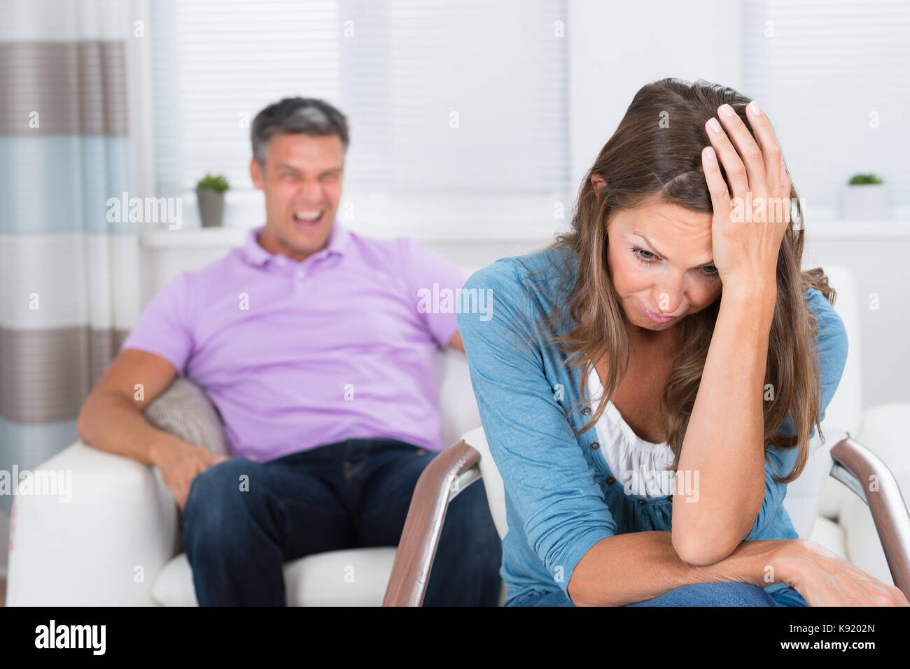 Reifer Mann zu schreien Der frustrierte Frau sitzt auf Stuhl Stockfoto