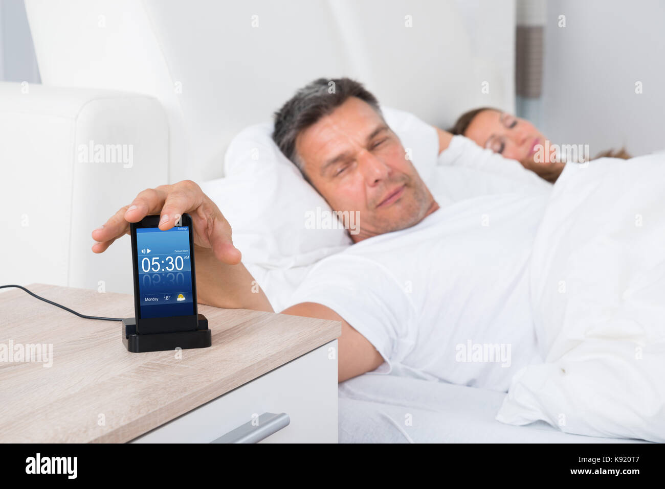 Finger Schlafen Ein Beim Handy Halten Mann auf dem Bett dösen Wecker auf Handy Bildschirm beim Schlafen