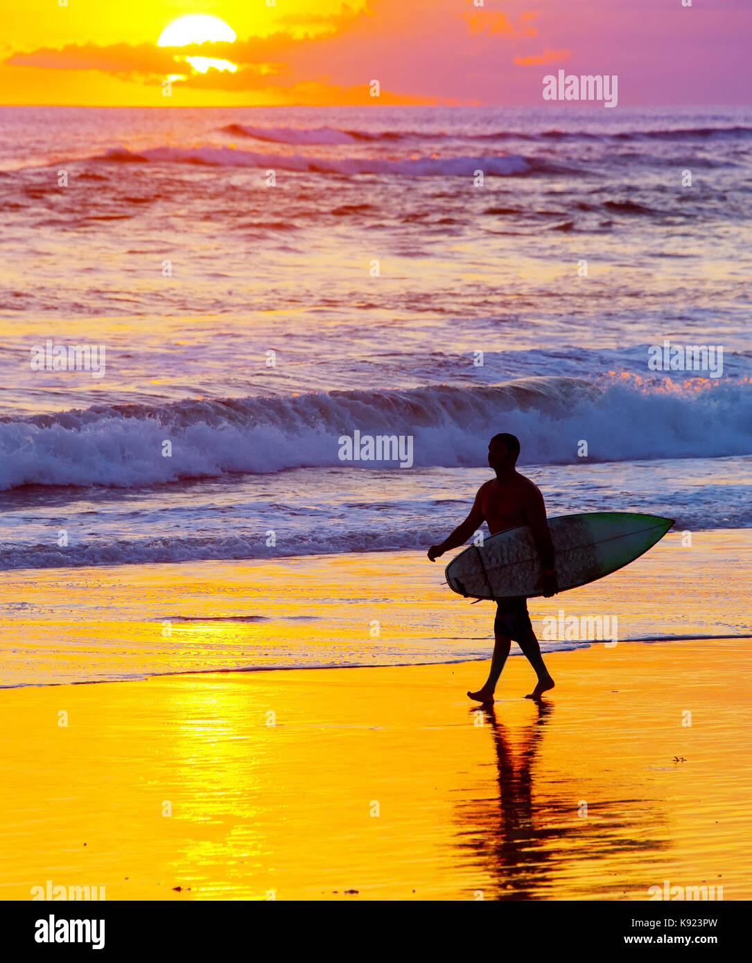 Surfer mit Surfbrett zu Fuß am Strand bei Sonnenuntergang. die Insel Bali, Indonesien Stockfoto