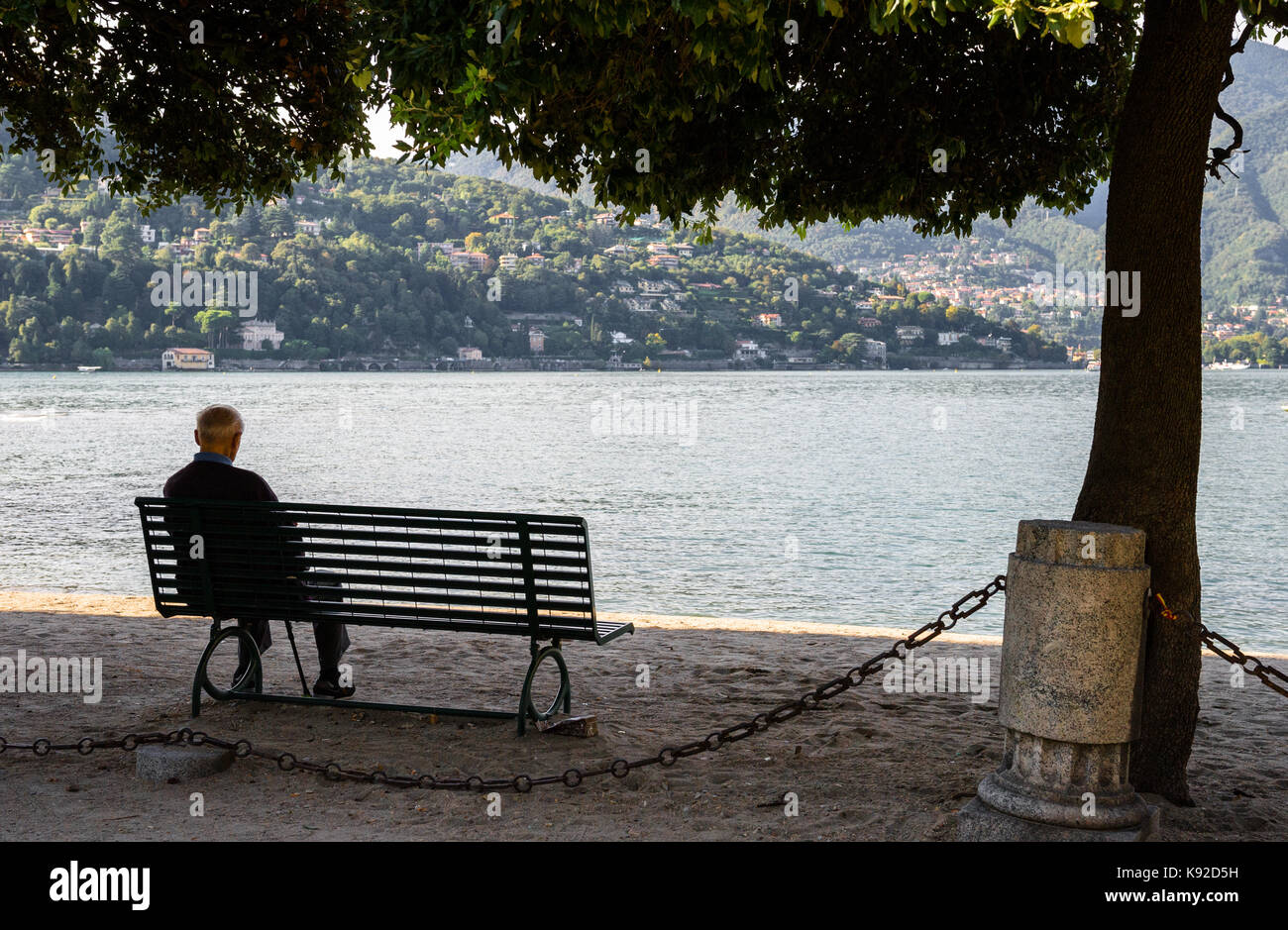 Ältere Männer sitzen auf einer Parkbank am Ufer am Comer See, Italien Stockfoto
