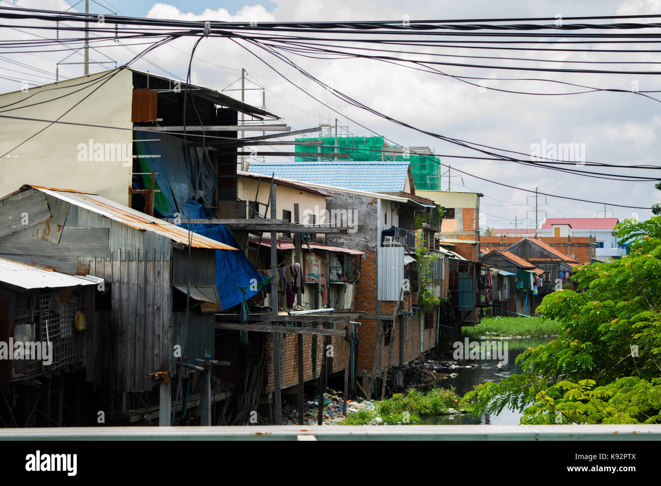 Ein Wasser Seite Bereich in Phnom Penh Kambodscha, mit schlecht gebauten Häuser mit Wellblech Decken und Wände, die auf verschmutztes Wasser. Stockfoto