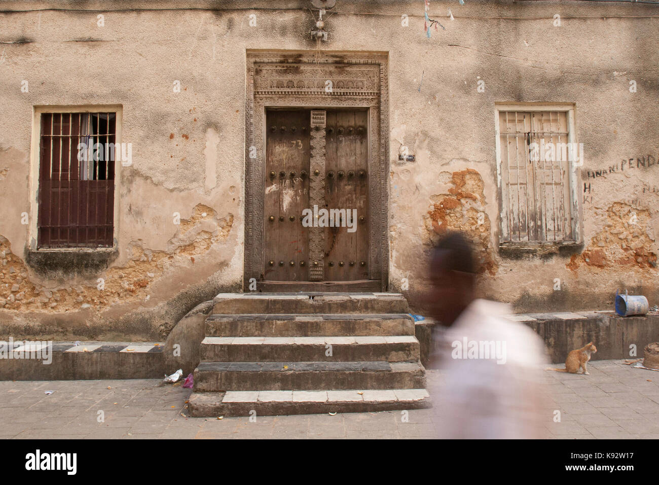 Ein Mann, der an einer traditionellen Swahili-Tür, Stone Town, Sansibar, Tansania, Ostafrika, vorbeigeht Stockfoto