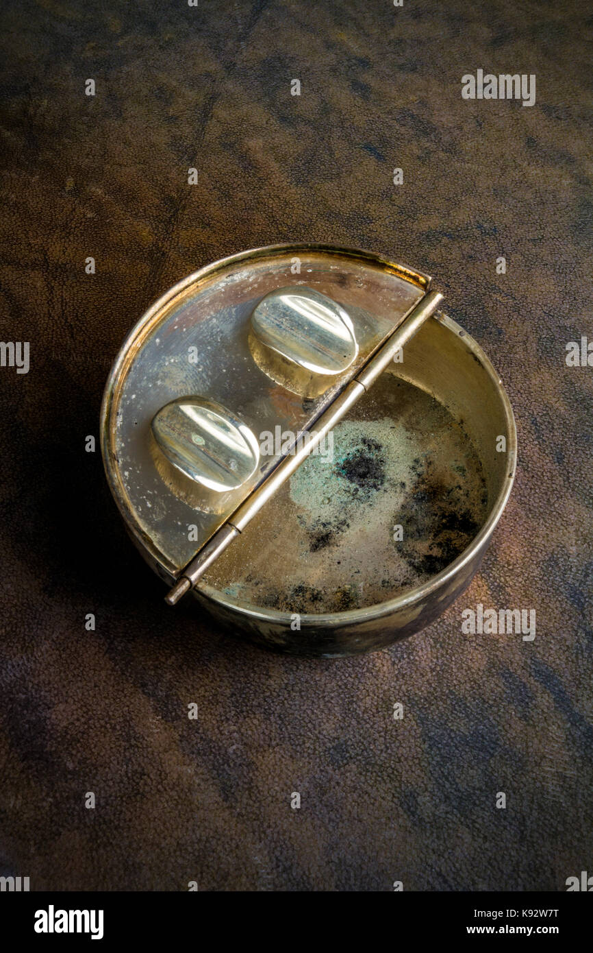 Antike tragbares Metall pocket Aschenbecher auf ein dunkles Braun Leder Hintergrund Stockfoto