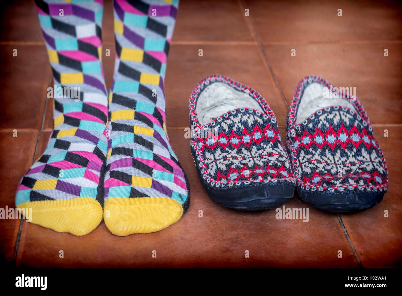 Frau, die mit farbigen Socken neben einem Winter Hausschuhe Stockfoto