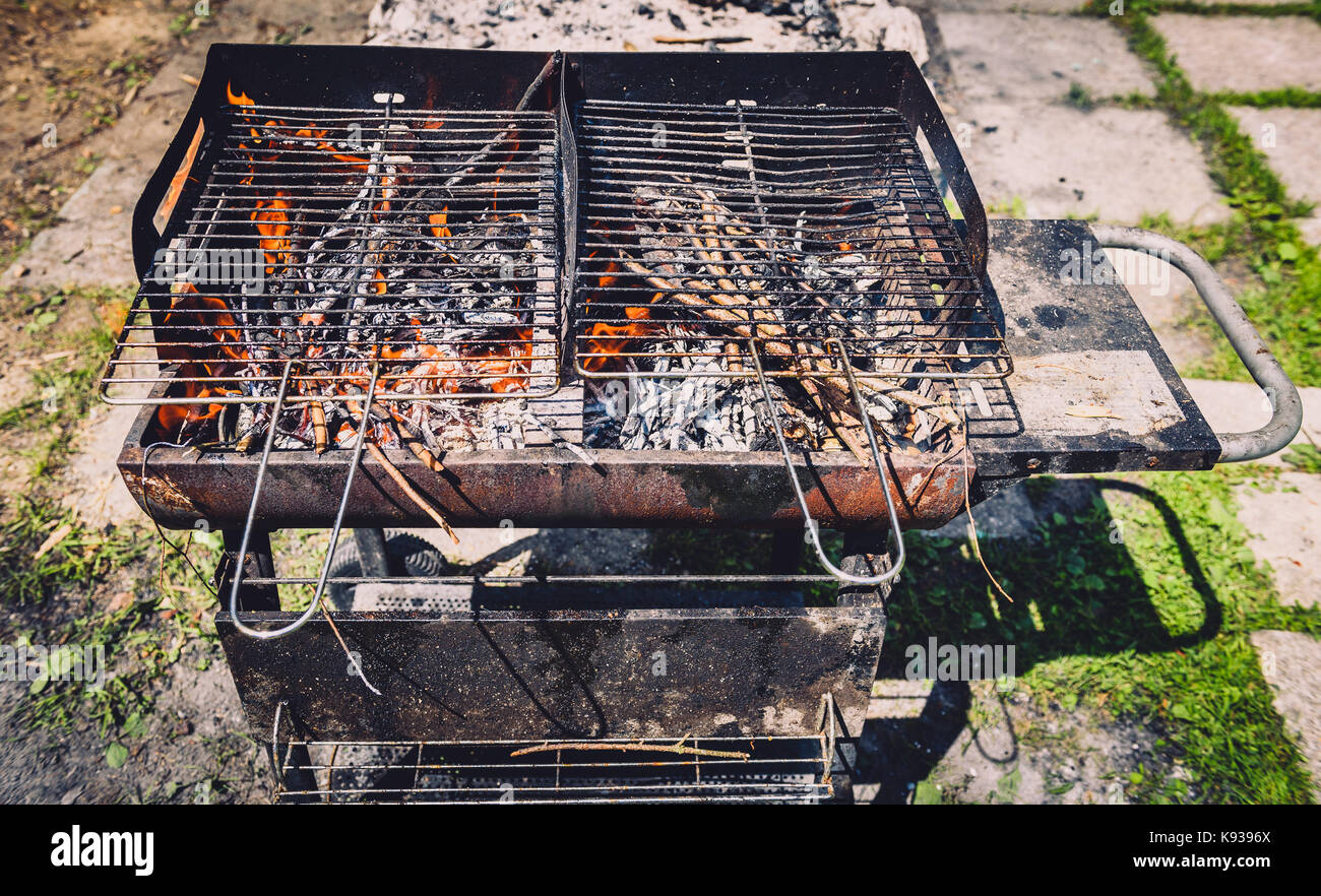 Brennen und alten rostigen Grill vorheizen grill Reinigung schmutziger Raster. Flammen im Grill in der Natur - Picknick im Freien. Holzkohle vorbereiten auf den Grill Stockfoto
