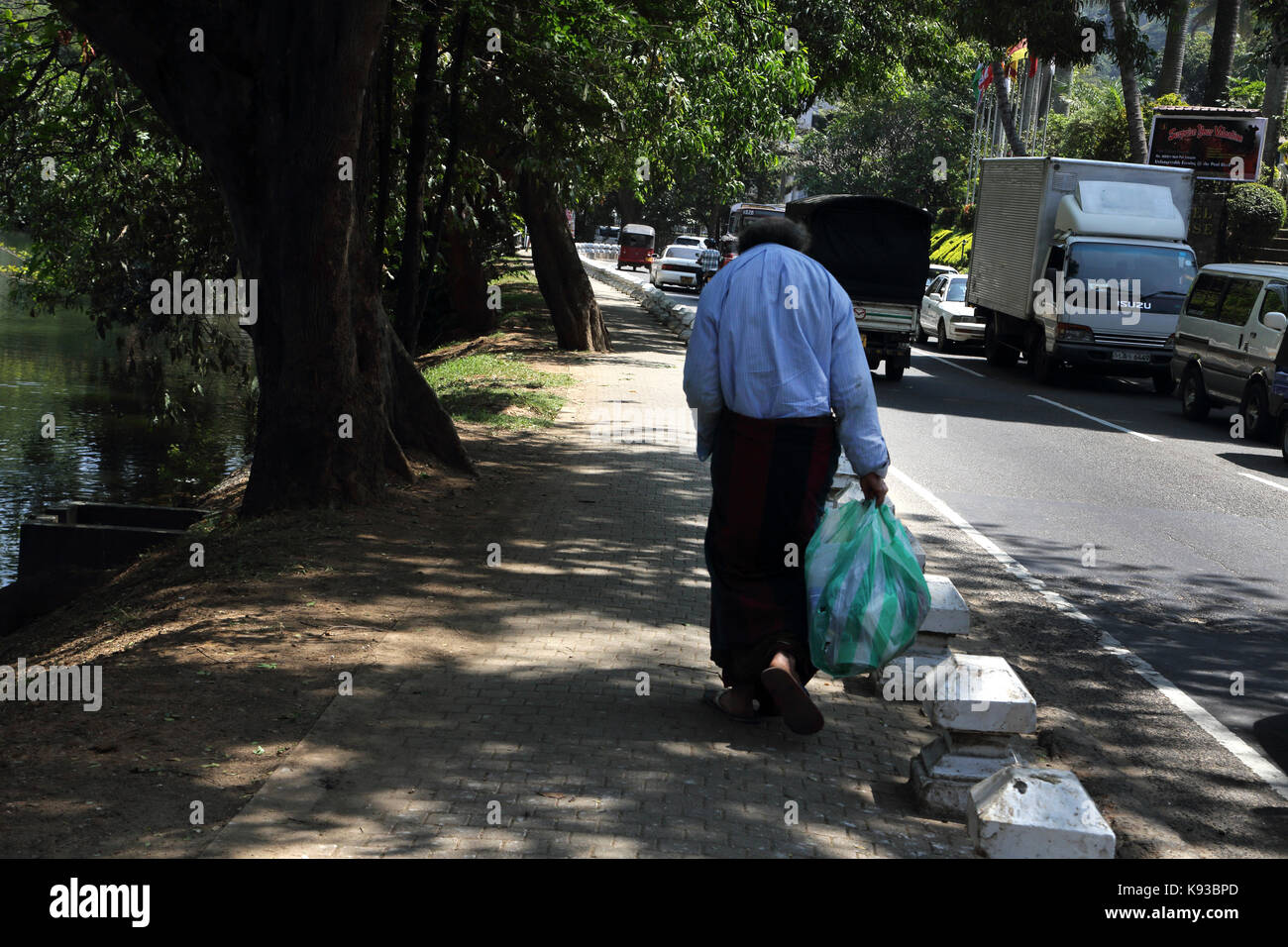 Kandy Sri Lanka Mann Tragetasche zu Fuß durch befahrene Straße vom See von Kandy Stockfoto