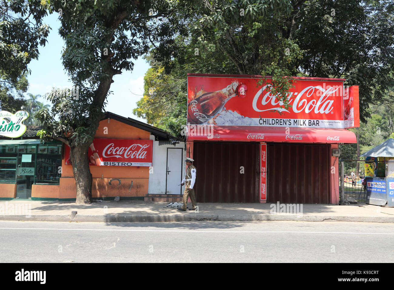 Kandy Stadt Sri Lanka Polizisten zu Fuß durch Kinder Milch Bar Werbung Coca Cola Stockfoto