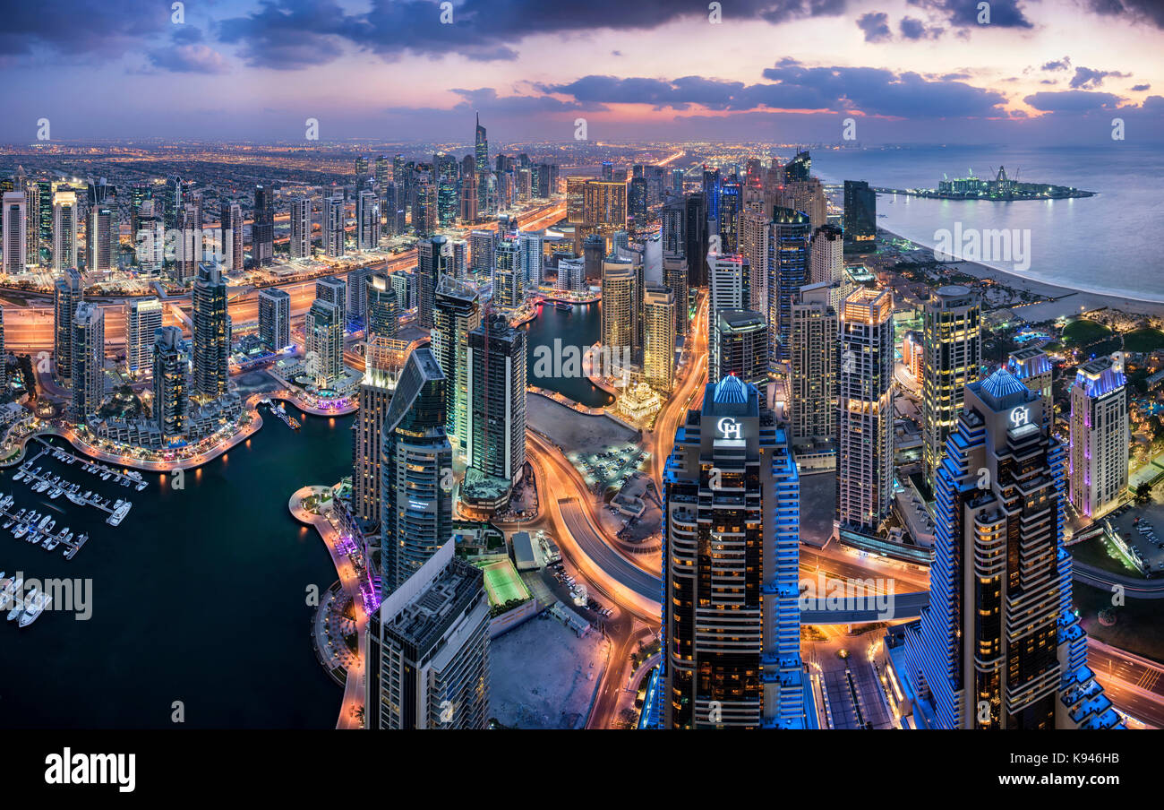 Luftaufnahme von das Stadtbild von Dubai, Vereinigte Arabische Emirate bei Dämmerung, mit beleuchteten Wolkenkratzer und den Jachthafen im Vordergrund. Stockfoto
