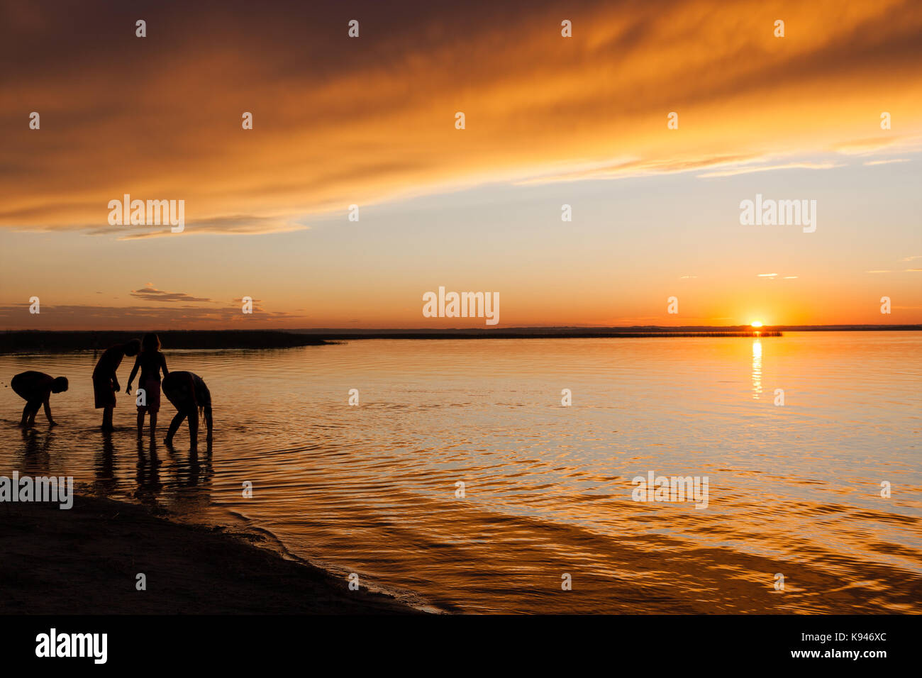 Silhouette der Kinder spielen am Wasser am Strand bei Sonnenuntergang. Silhouette Umrisse in Photoshop modifizierte Personen nicht identifizierbar zu machen. Stockfoto