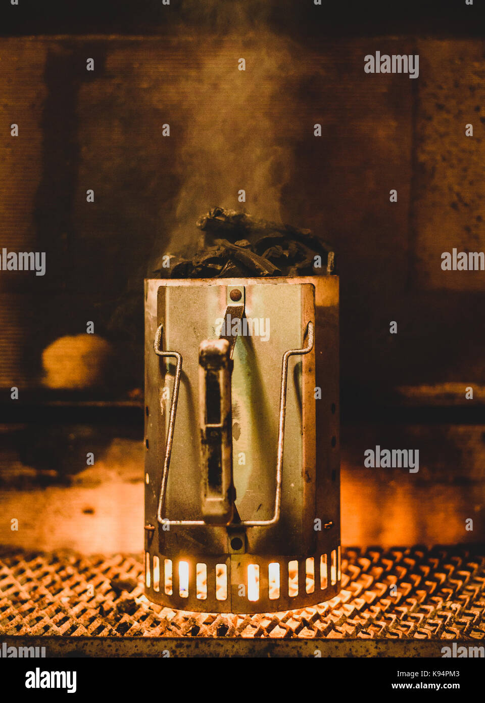 Vorbereitung Grill Kohle oder Briketts in Chimney Starter in der Nacht. Starten Kohlen für Grill innerhalb von Kamin mit speziellen Fire Starter. Flammen auf Stockfoto