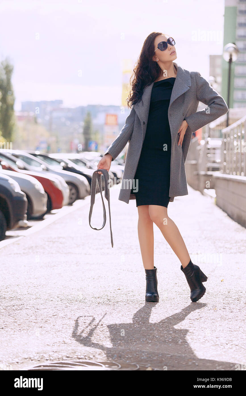 Outdoor portrait einer jungen schönen modischen Frau, im Freien. Ein Modell in einem stilvollen grauen Mantel bekleidet, Sonnenbrillen. Das Konzept der Damenmode, urban Lifestyle Stockfoto