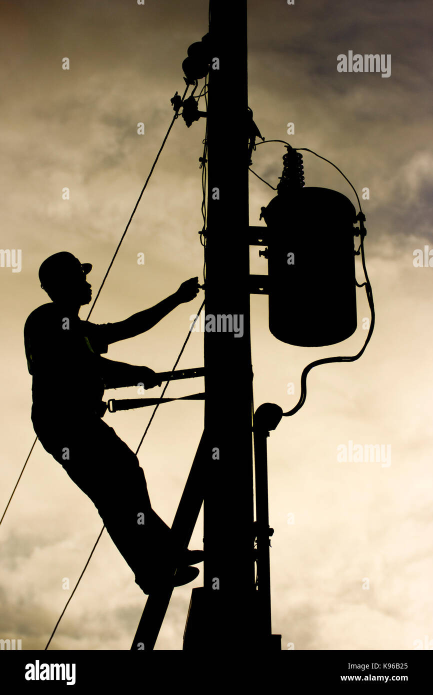 Mann bei der Arbeit über Power line Post sichern einen Transformator Stockfoto