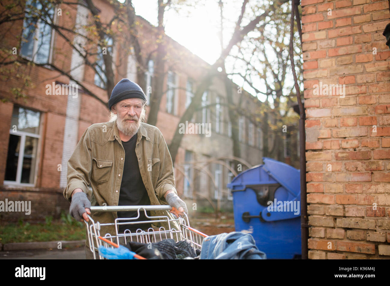 Anzeigen von Obdachlosen alten Mann mit Einkaufswagen aus dem Supermarkt. Stockfoto