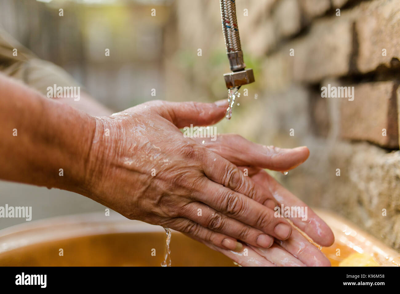 Nahaufnahme von Obdachlosen waschen ihre Hände unter fließendem Wasser, Stockfoto