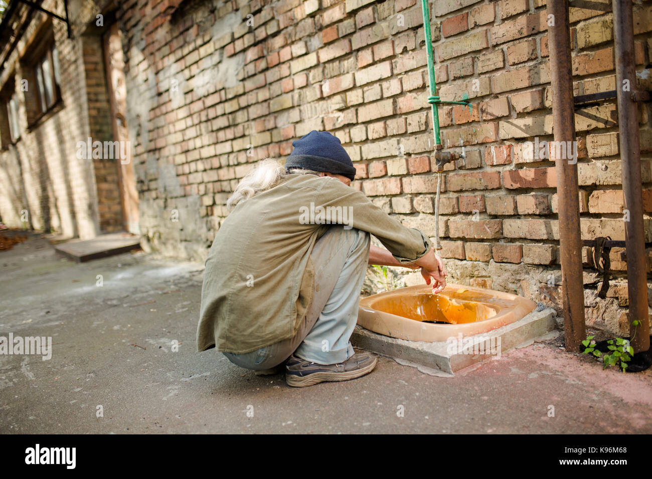 Obdachloser squating Hände zu waschen. Stockfoto
