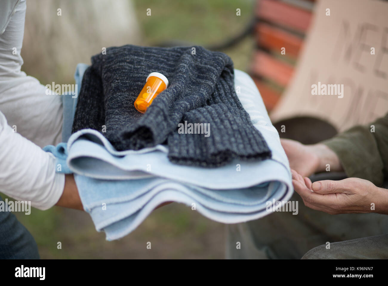 Nahaufnahme der Hände mit warmer Kleidung, Handtuch und Medizin für die Obdachlosen. Stockfoto