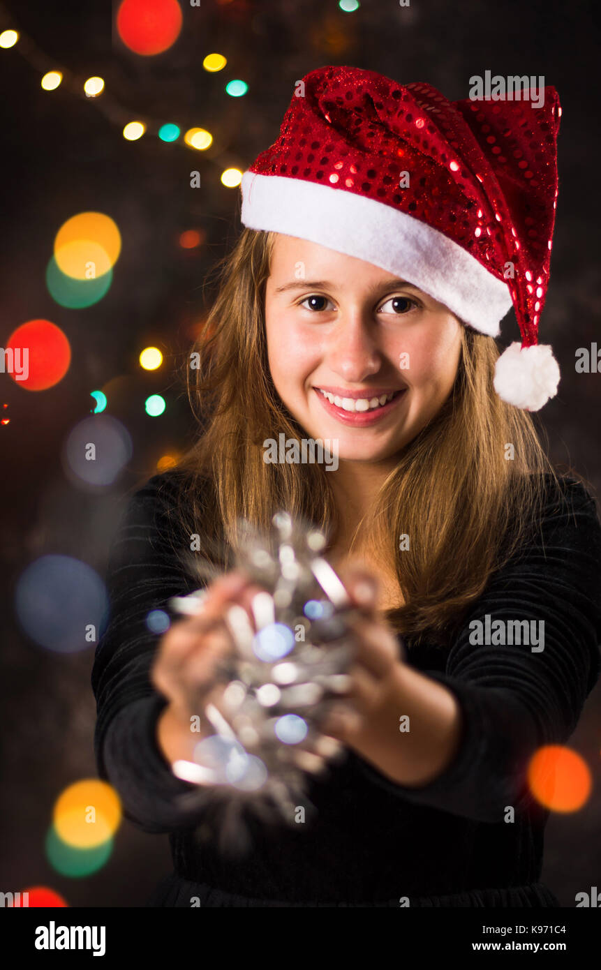 Junges Mädchen mit Weihnachtsmütze Holding glänzenden Christbaumschmuck Stockfoto