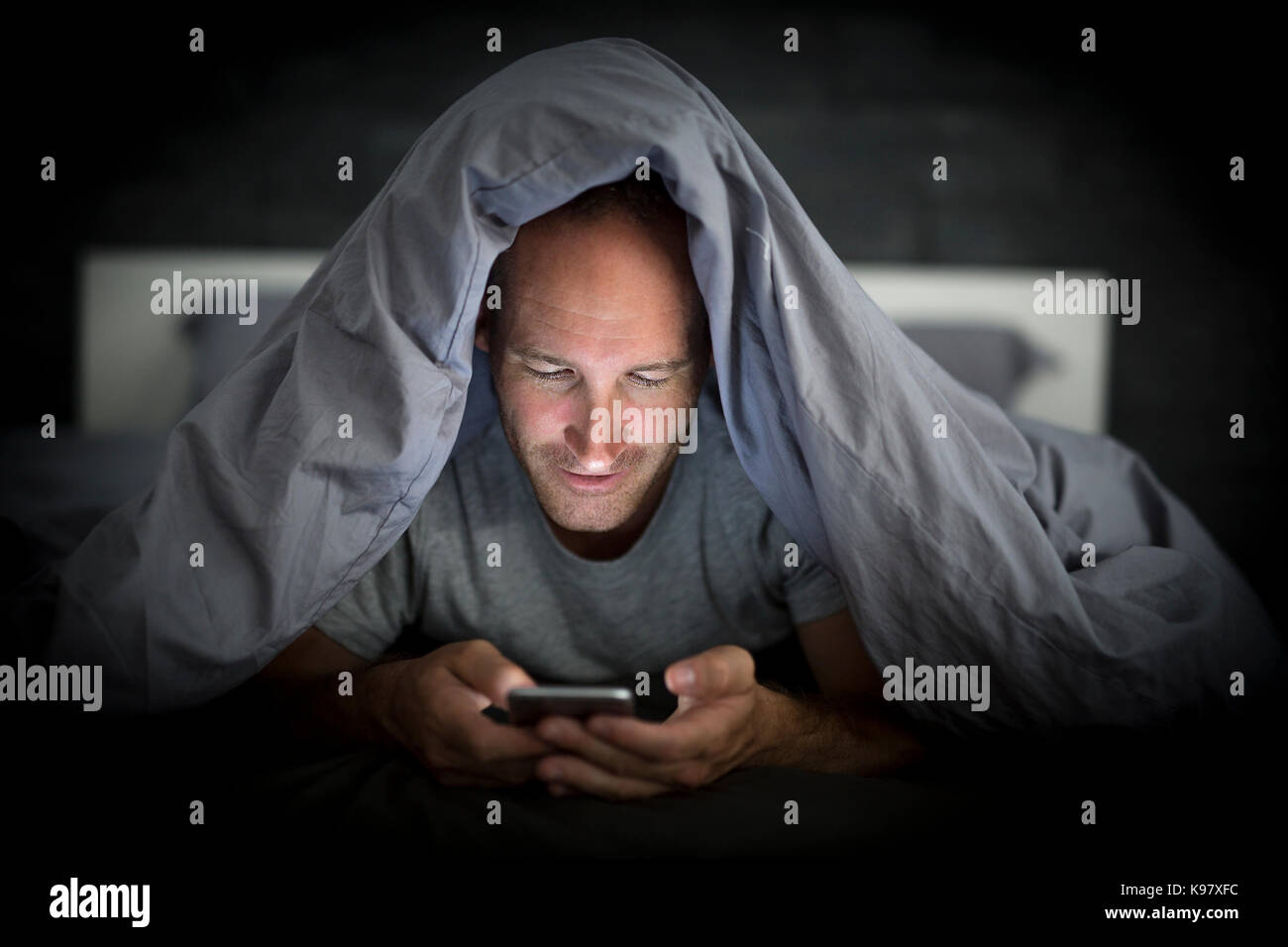 Junge Handy süchtiger Mensch wach bis spät in die Nacht im Bett mit Smartphone Stockfoto