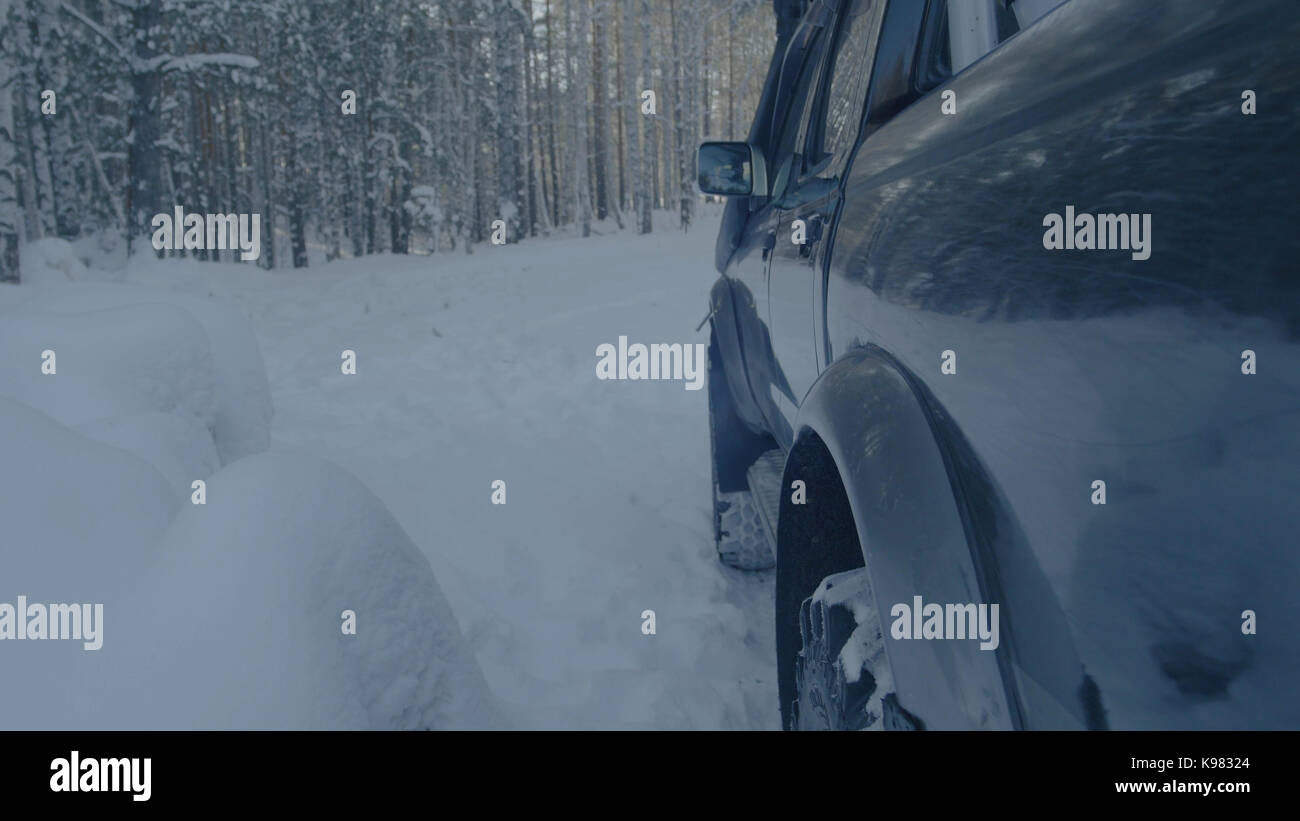 Jeep reitet auf dem Schnee in den Wald Nahaufnahme. Stockfoto