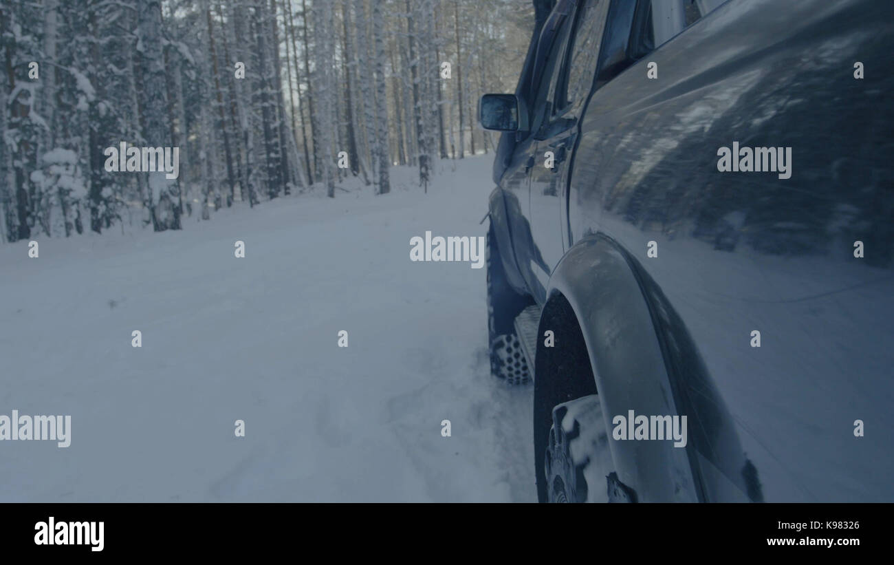 Jeep reitet auf dem Schnee in den Wald Nahaufnahme. Stockfoto
