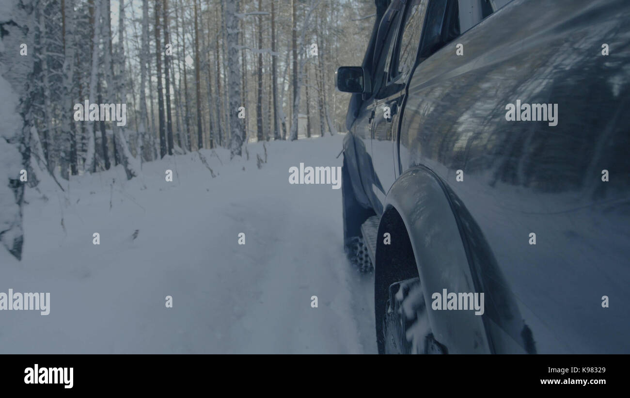 Jeep reitet auf dem Schnee in den Wald Nahaufnahme. Stockfoto