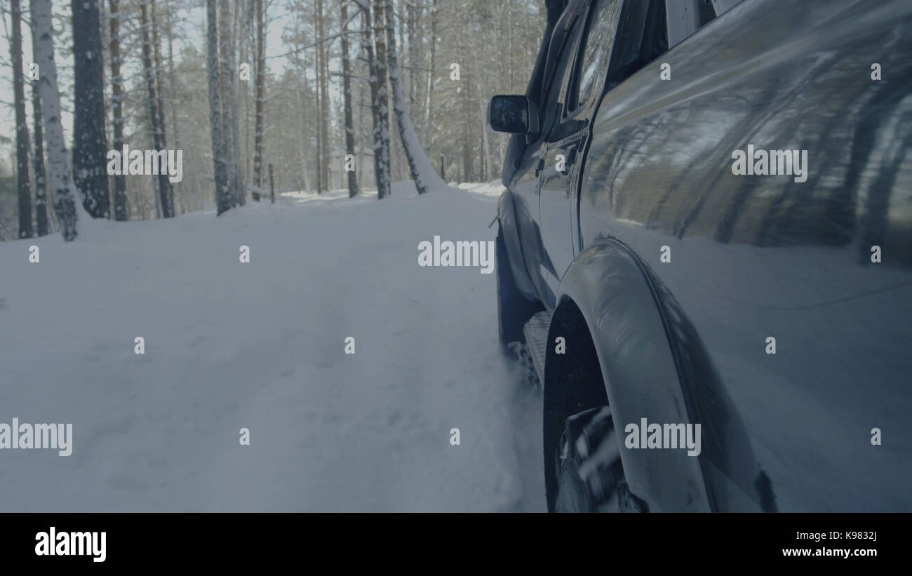 Jeep reitet auf dem Schnee in den Wald Nahaufnahme. Stockfoto