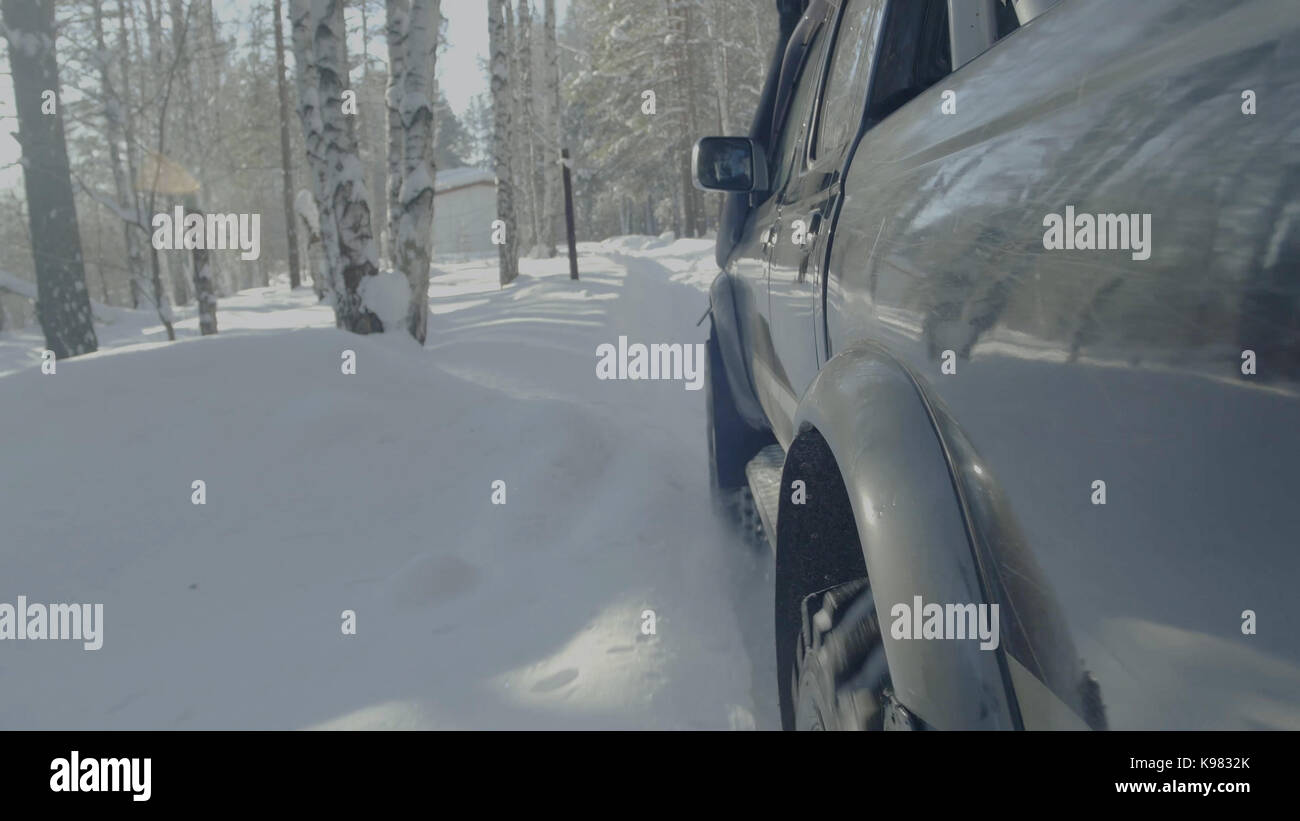 Jeep reitet auf dem Schnee in den Wald Nahaufnahme. Stockfoto