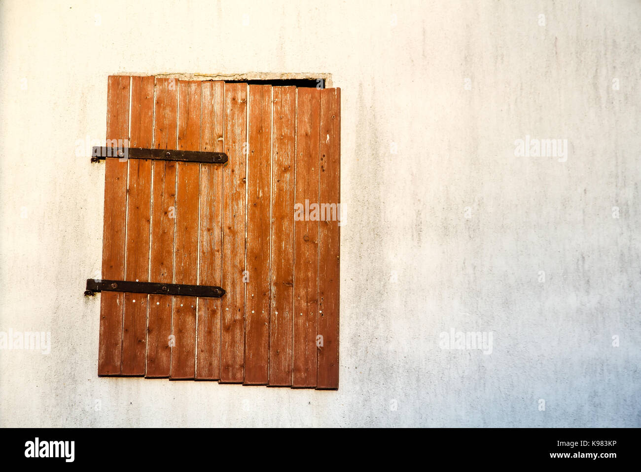 Braun rot Holz- Fenster mit verrosteten Scharniere aus Metall auf einem weißen Zement Wand detail. Das alte Fenster hängt neigen und nur teilweise schließen der Wand, Bo Stockfoto