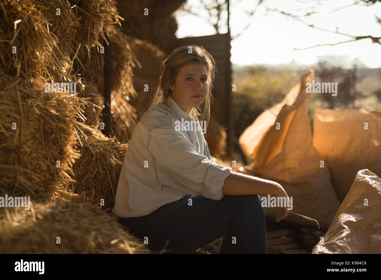 Portrait von selbstbewussten jungen Frau sitzt auf der Heuballen auf der Farm Stockfoto