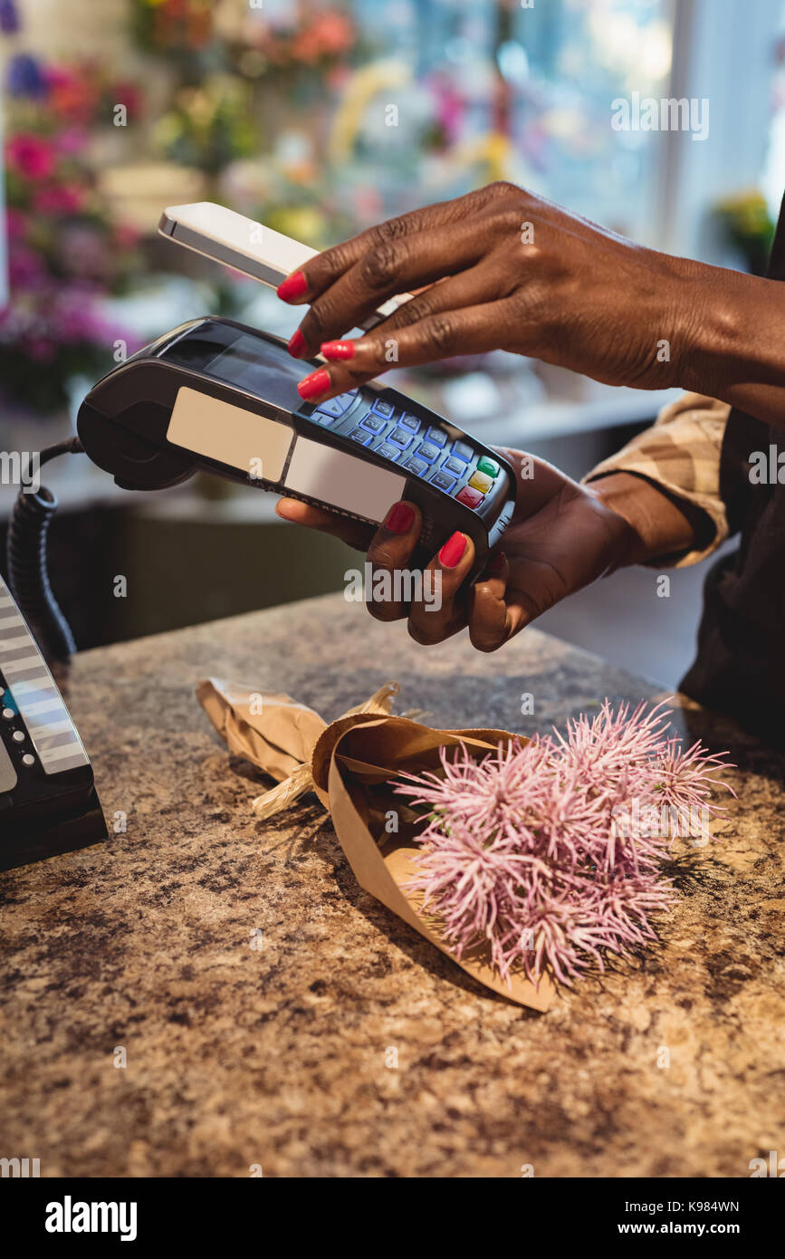 Hand des Kunden die Zahlung durch Smartphone in die Flower Shop Stockfoto