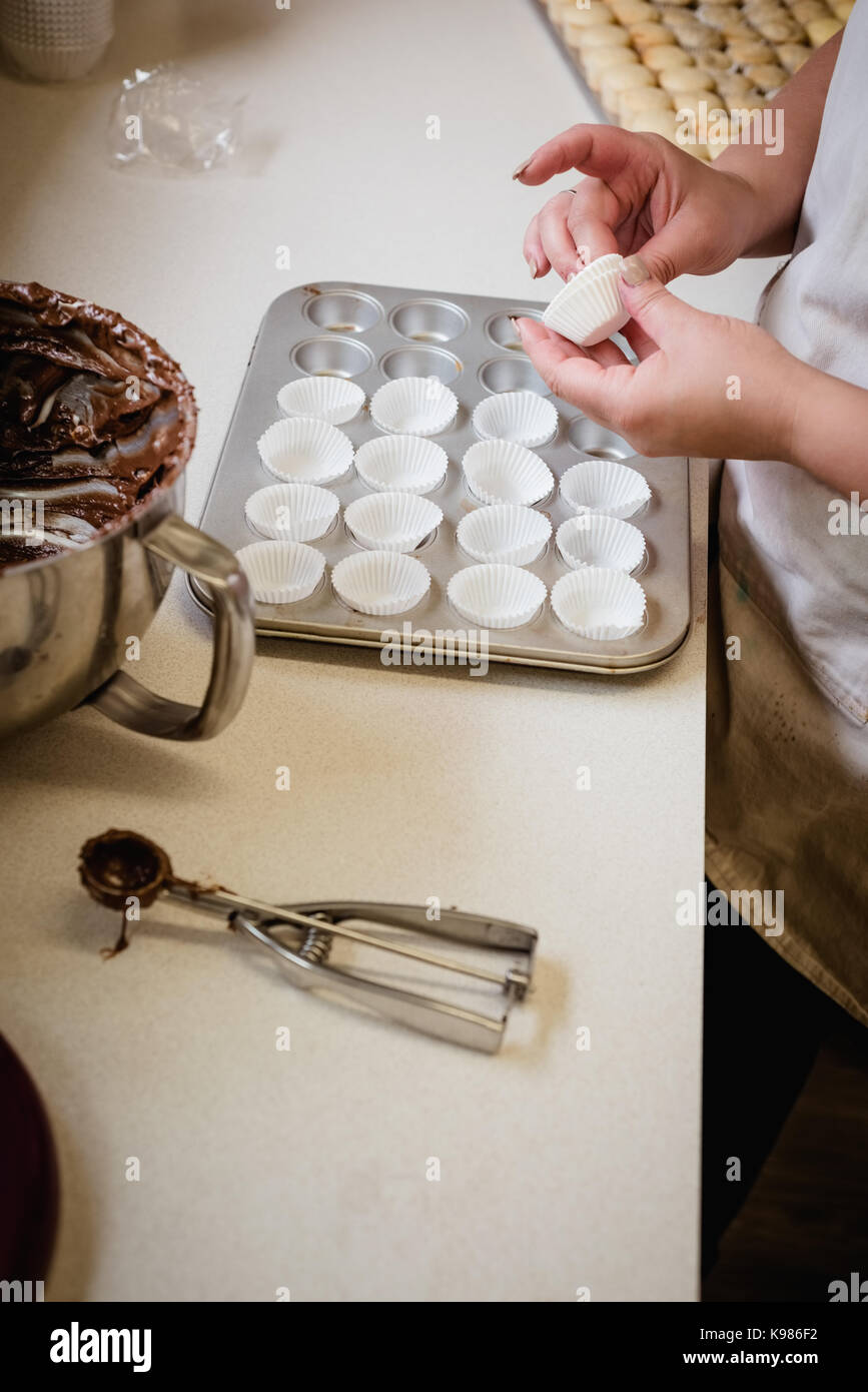 Frau Platzieren der muffin Papier Fall auf das Backblech in der Küche Stockfoto