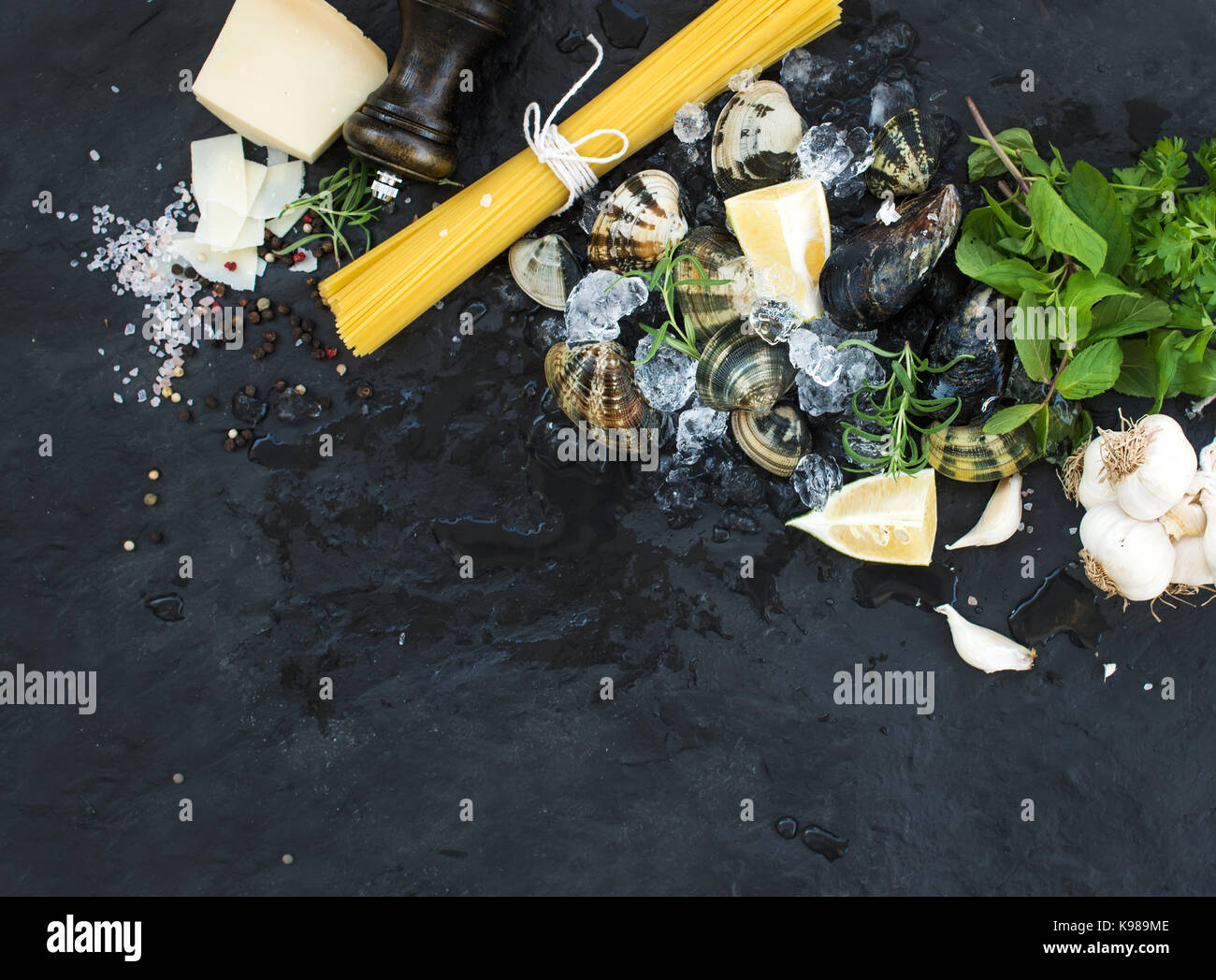 Zutaten für Spaghetti Vongole kochen. Muscheln auf abgebrochene Eis, rohe  Nudeln, Parmesan-Käse, Knoblauch, Petersilie und Zitrone über Stein  Schiefer Hintergrund, Ansicht von oben Stockfotografie - Alamy