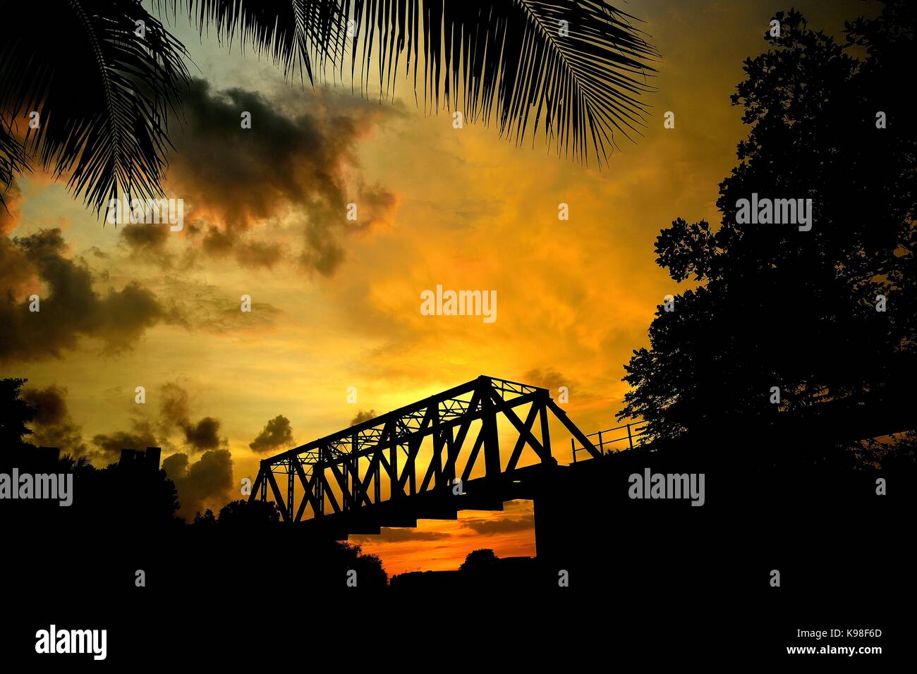 Kastenträger Brücke im Dschungel gegen einen genialen Sonnenuntergang Silhouette Stockfoto