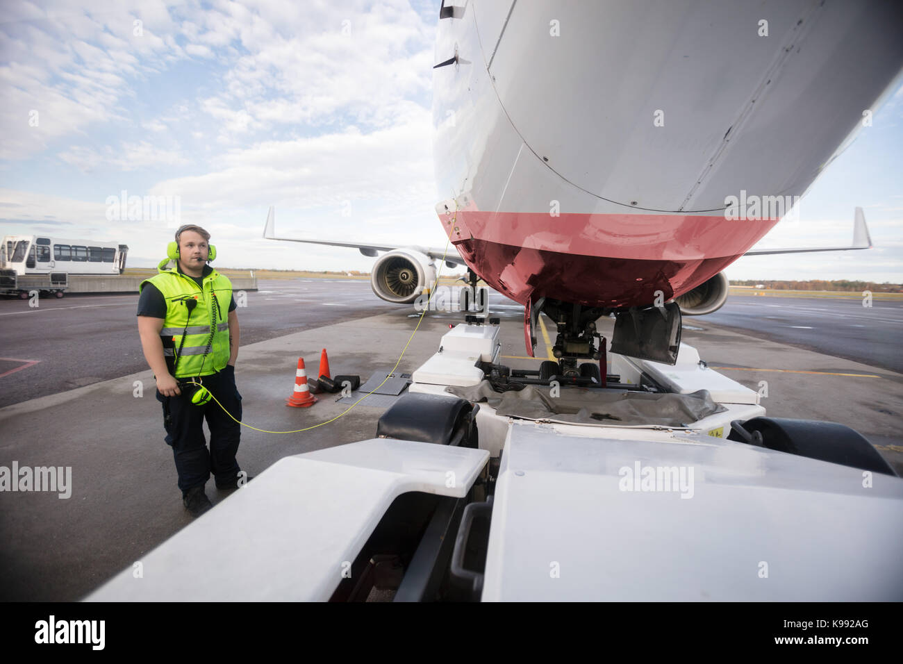 Arbeitnehmer stehen mit dem Flugzeug mit Kommunikation Kabel auf Start- und Landebahn Stockfoto