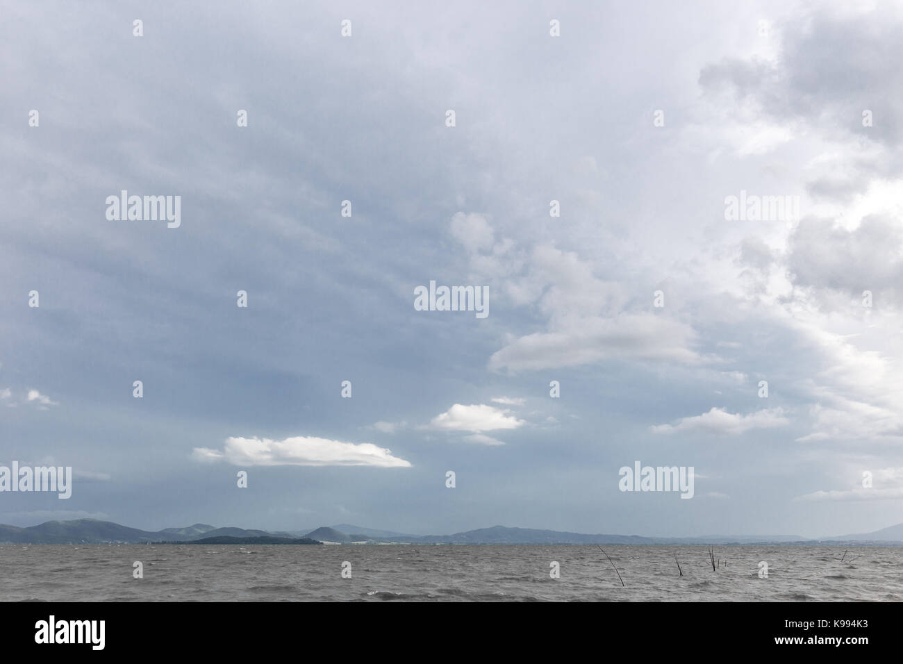 See auf einem Moody Tag mit sehr weiße Wolken über eine Insel Stockfoto