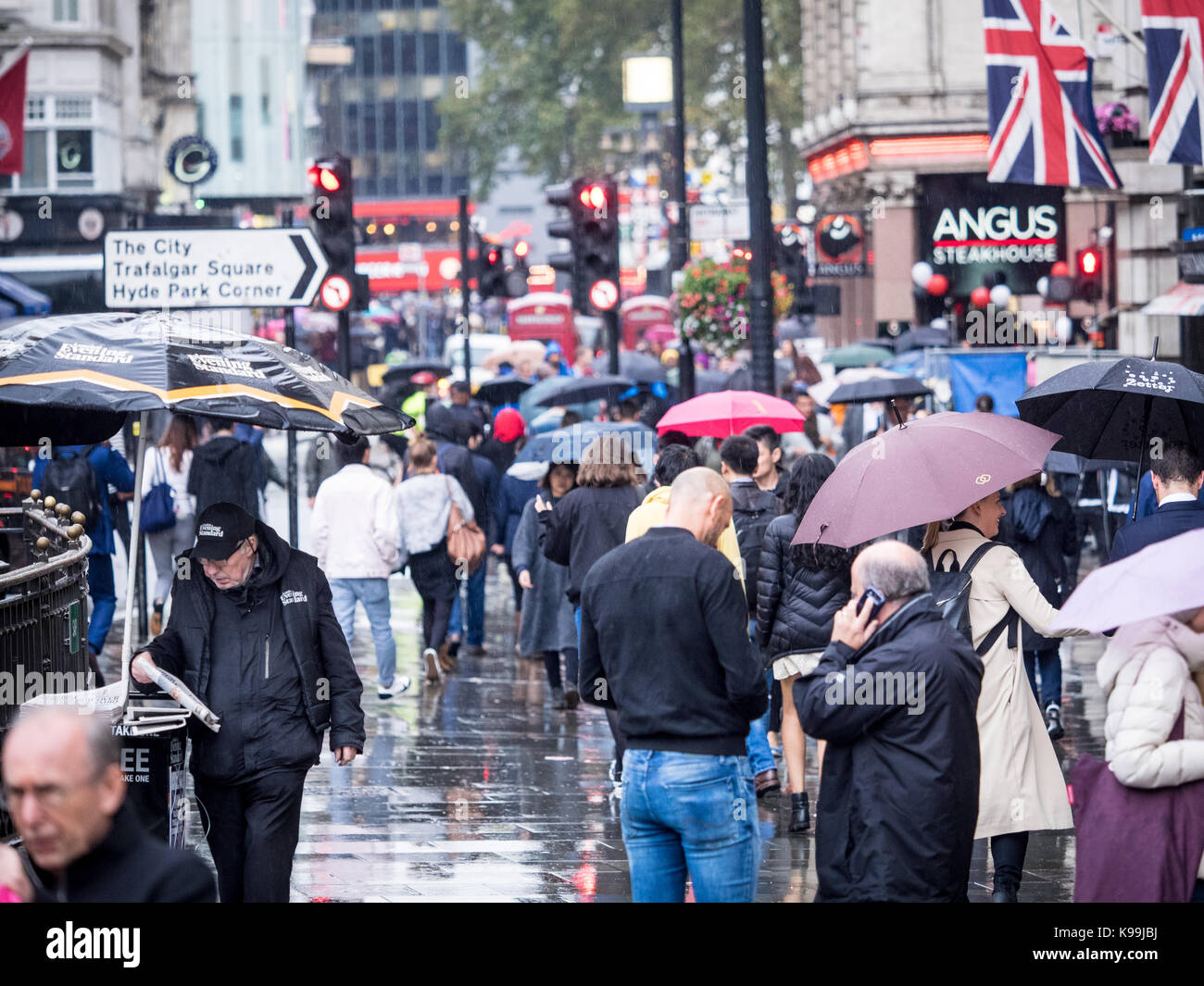 London im Regen - Touristen und Arbeiter der Regen in der Nähe der Londoner Leicester Square brave in Soho Stockfoto