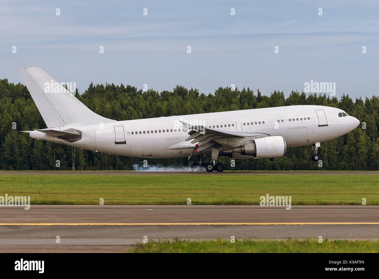 Die großraumflugzeuge Flugzeug Landung auf der Start- und Landebahn am Flughafen vor dem Hintergrund des Waldes und blauer Himmel. Sommer sonnige Wetter. Der Moment der Berührung Stockfoto