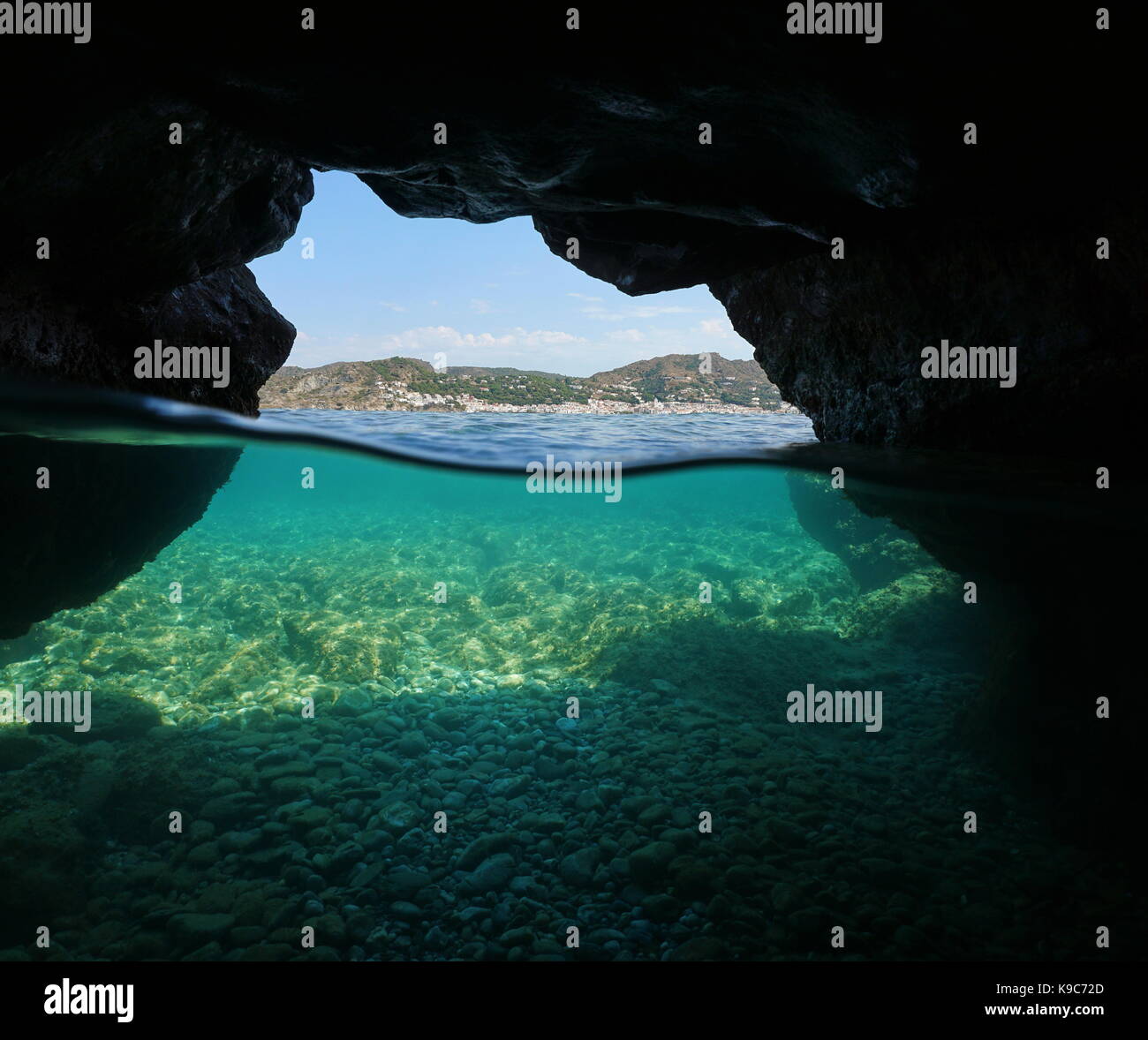 Über und unter dem Meer in eine Höhle an der Küste mit der mediterranen Dorfes El Port de la Selva und Kieselsteinen Unterwasser, Spanien, Costa Brava Stockfoto