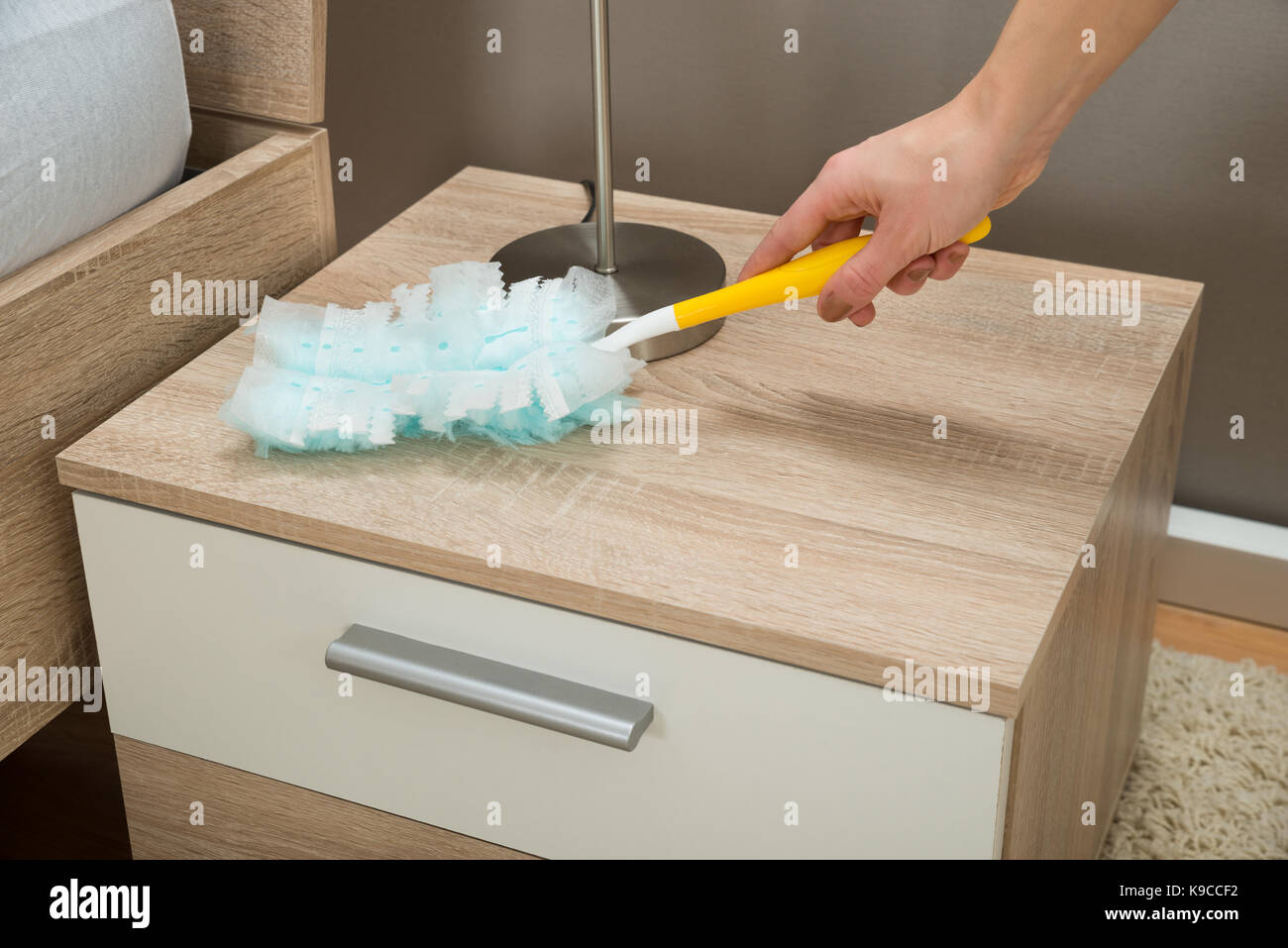 Nahaufnahme der Hand Entfernen von Staub vom Nachttisch mit Feather Duster Stockfoto