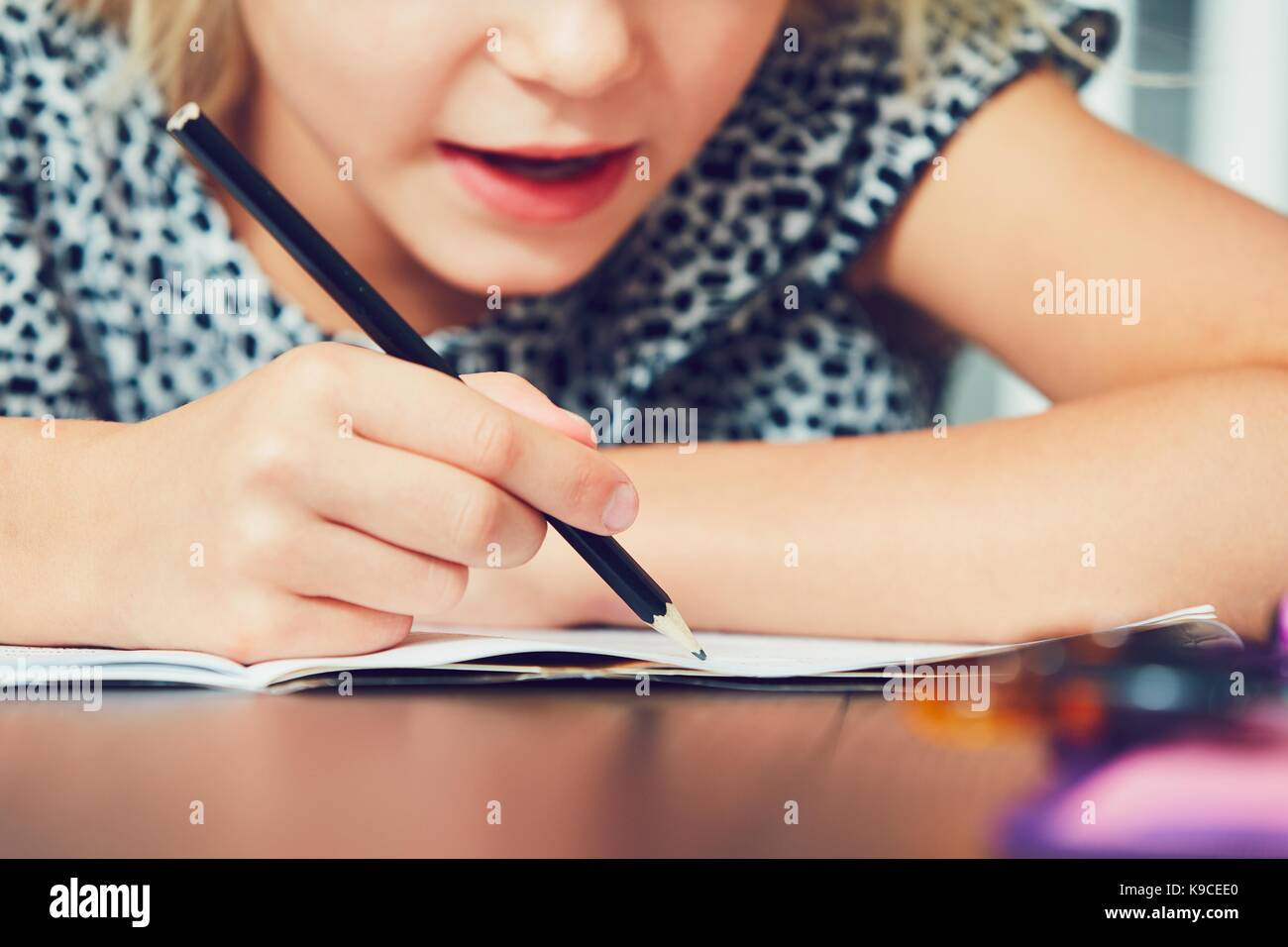 Kleines Mädchen schreiben seine Hausaufgaben für die Grundschule. Stockfoto
