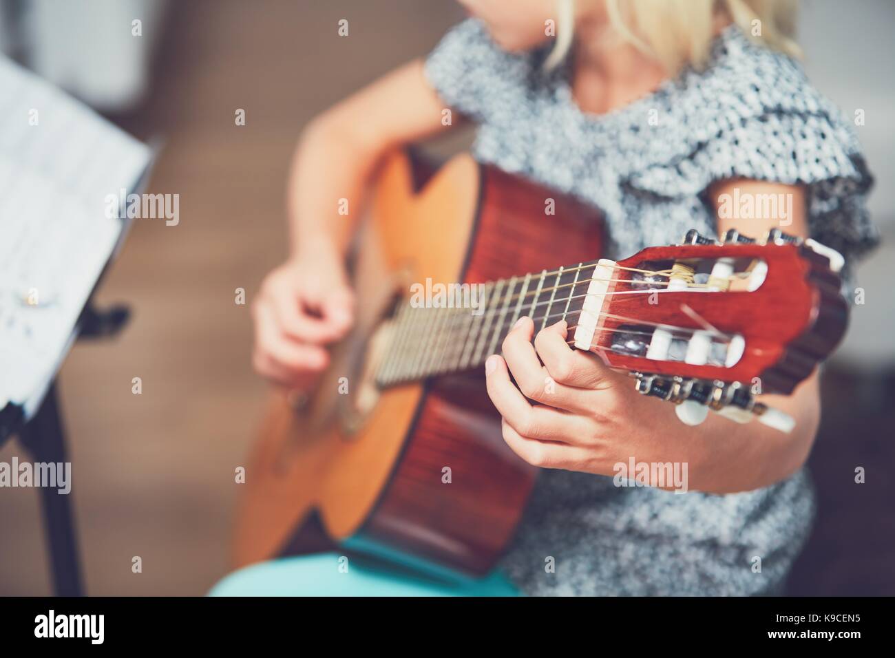 Kleines Mädchen lernen der Gitarre zu Hause zu spielen. Selektiver Fokus auf die Zeichenfolge. Stockfoto