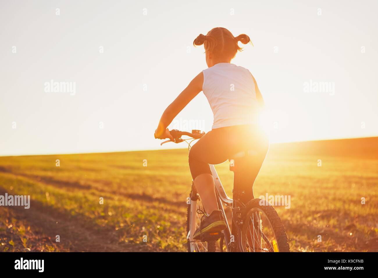 Silhouette der Mädchen mit dem Fahrrad auf den Sonnenuntergang. Sommer Reise in die Landschaft. Stockfoto